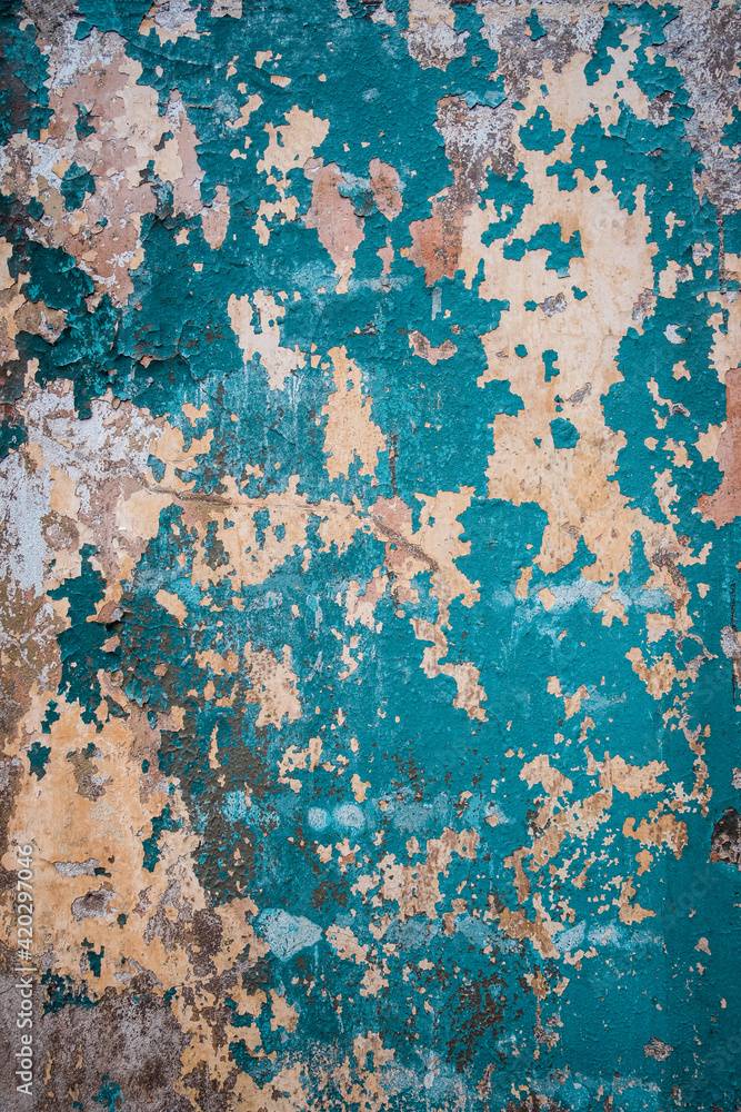 Abstract grunge texture of old colorful wall with peeled off blue paint. Creative background. Green, grey, blue and orange rough weathered stone texture with stucco and paint. Vertical, copy space