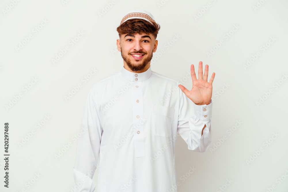 Young Arab man wearing the typical arabic costume isolated on white background smiling cheerful showing number five with fingers. Young Arab man wearing the typical arabic costume isolated on white background smiling cheerful showing number five with fingers.
