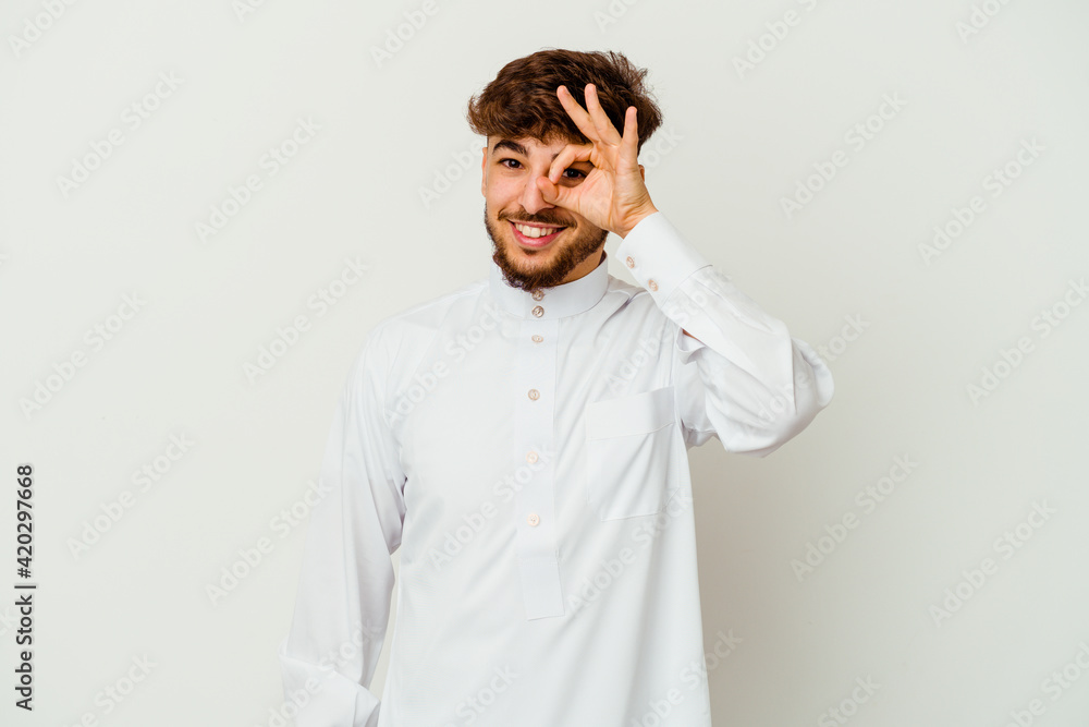 Young Moroccan man wearing a typical arab clothes isolated on white background excited keeping ok gesture on eye. Young Moroccan man wearing a typical arab clothes isolated on white background excited keeping ok gesture on eye.