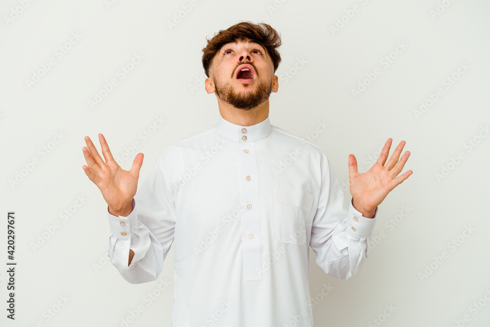 Young Moroccan man wearing a typical arab clothes isolated on white background screaming to the sky, looking up, frustrated. Young Moroccan man wearing a typical arab clothes isolated on white background screaming to the sky, looking up, frustrated.