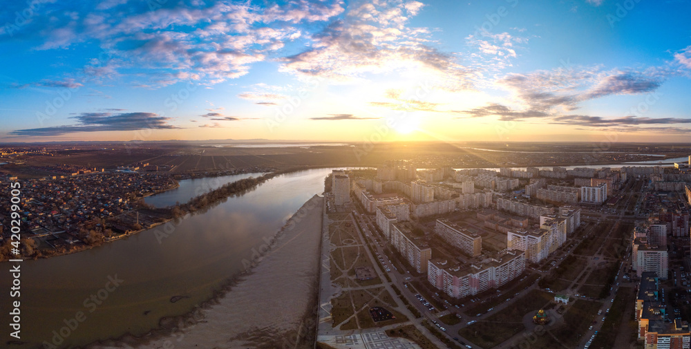 evening panoramic landscape of the sunset over the river near multi-storey buildings and streets of the city of Krasnodar with blue sky and beautiful clouds