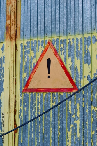 Warning sign on the Old shabby yellow painted metal wall