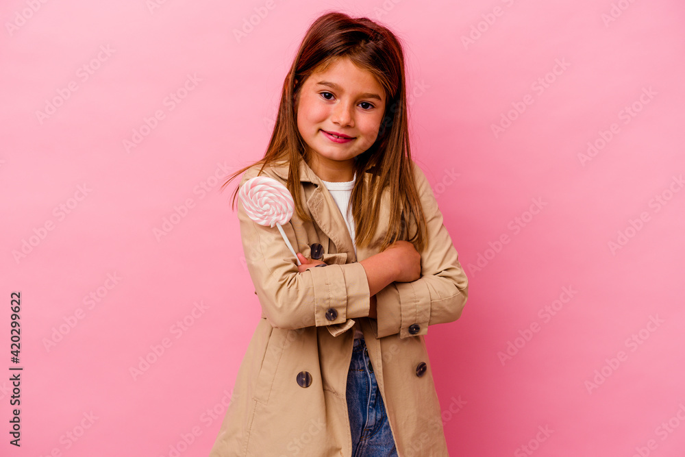 Little caucasian girl holding a lollipop isolated on pink background laughing and having fun. Little caucasian girl holding a lollipop isolated on pink background laughing and having fun.