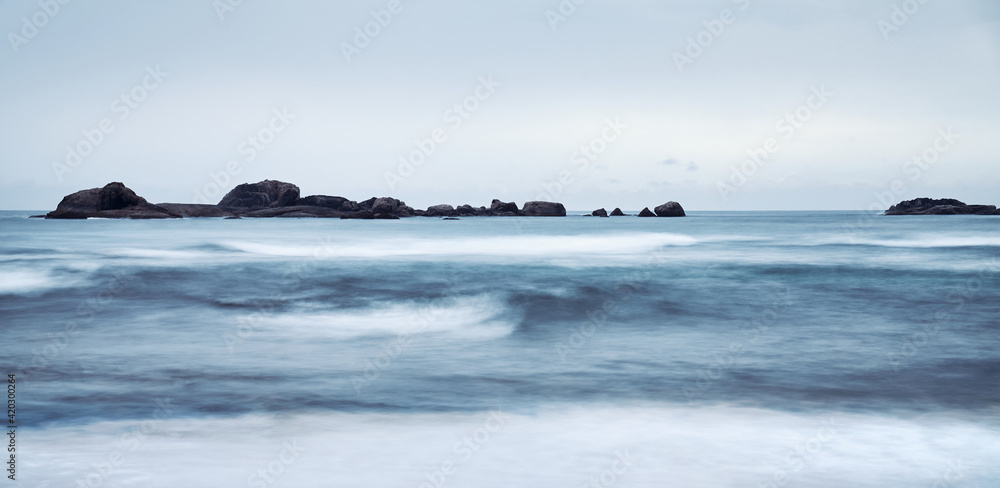 Long exposure picture of a seascape, focus on rocks, color toning applied.