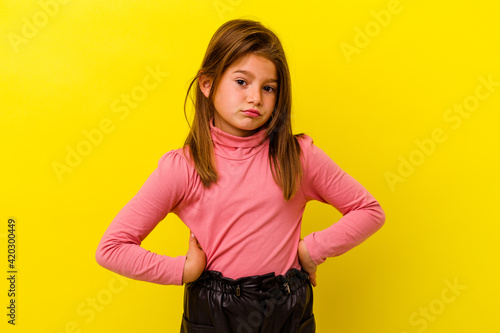 Little caucasian girl isolated on yellow background confused, feels doubtful and unsure.