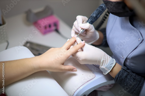 The girl master of nail service works with the client