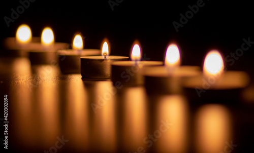 Closeup of many candles burning. The candle light is reflected