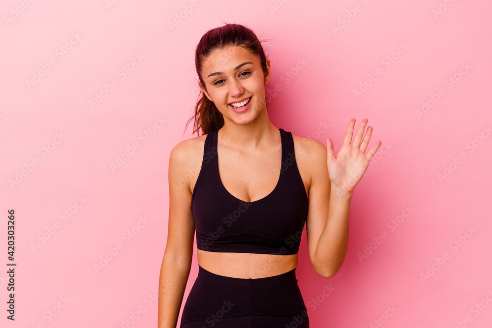Young sport Indian woman isolated on pink background smiling cheerful showing number five with fingers. Young sport Indian woman isolated on pink background smiling cheerful showing number five with fingers.
