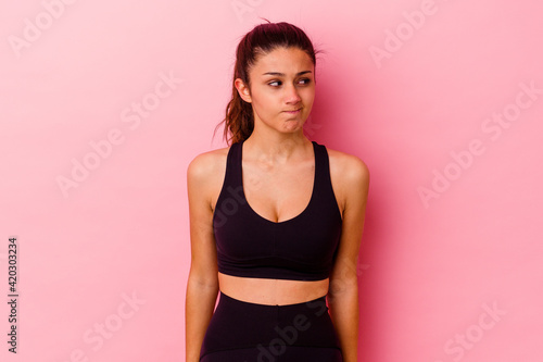 Young sport Indian woman isolated on pink background confused  feels doubtful and unsure.