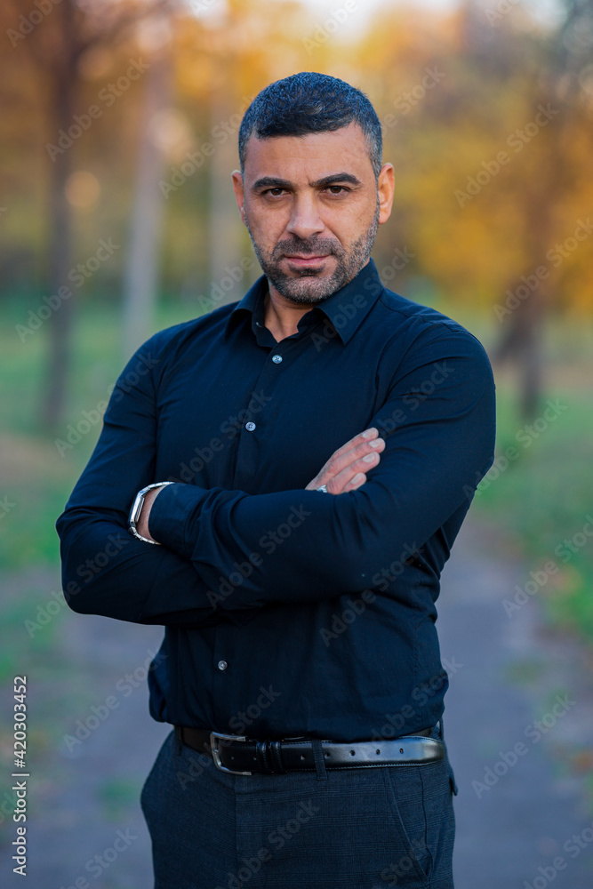 stylish man in black clothes stands in the park by the tree at sunset stylish man in black clothes stands in the park by the tree at sunset