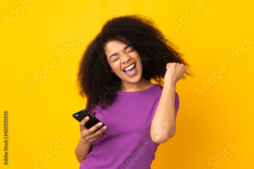 Young african american woman over isolated background with phone in victory position