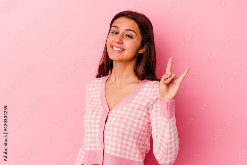 Young Indian woman isolated on pink background showing a horns gesture as a revolution concept. Young Indian woman isolated on pink background showing a horns gesture as a revolution concept.