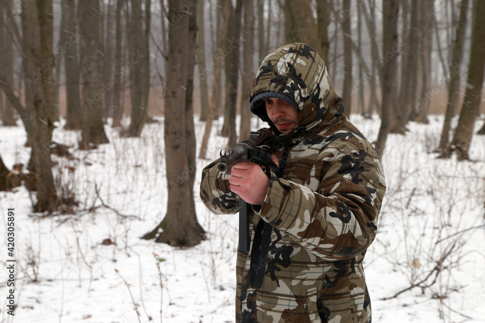 The man with vintage machine gun in the snowy forest