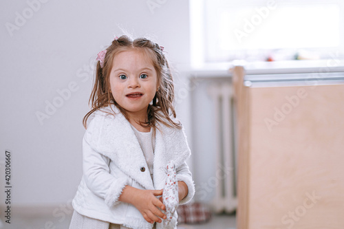 child girl with down syndrome with a toy in her hands looking happily at the camera