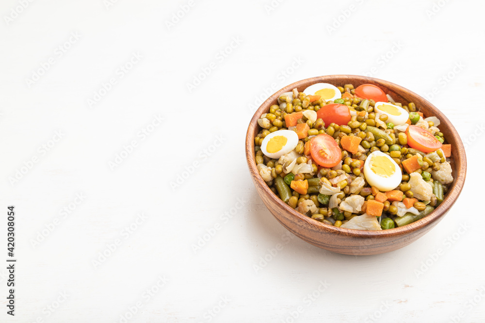 Mung bean porridge with quail eggs, tomatoes and microgreen sprouts on a white wooden background. Side view, copy space. Mung bean porridge with quail eggs, tomatoes and microgreen sprouts on a white wooden background. Side view, copy space.