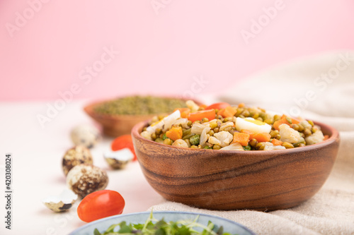 Mung bean porridge with quail eggs, tomatoes and microgreen sprouts on a white and pink background. Side view, selective focus, copy space.