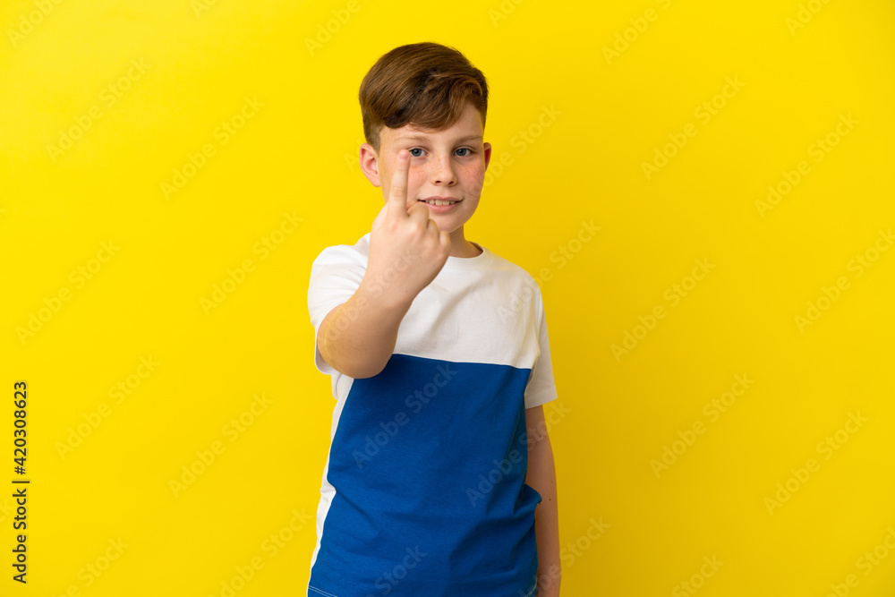 Little redhead boy isolated on yellow background doing coming gesture Little redhead boy isolated on yellow background doing coming gesture