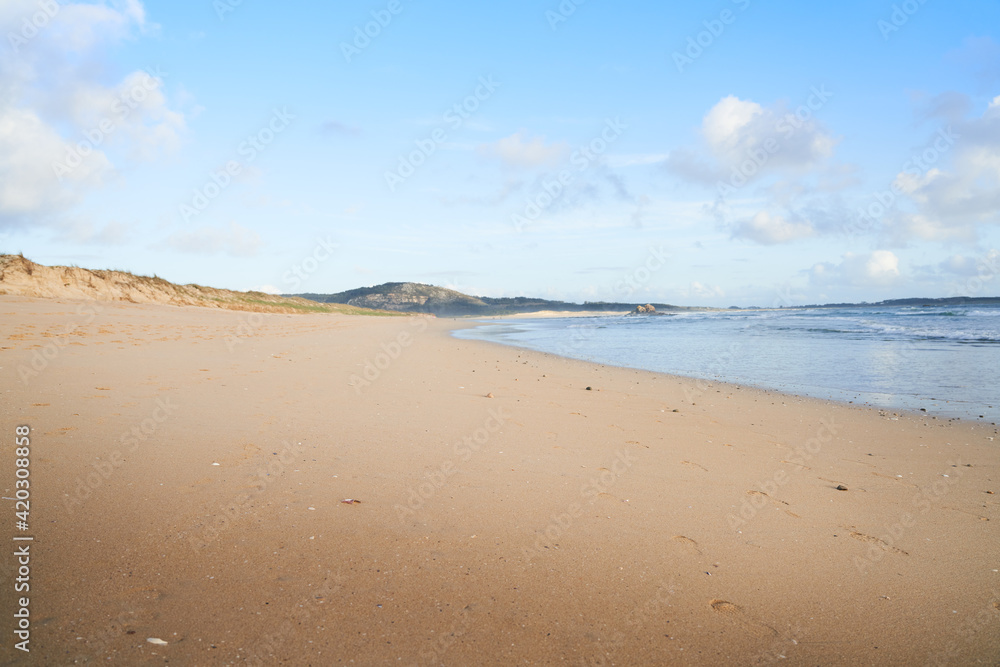 Playa muy grande de arena blanca con cielo azul y mar