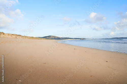 Playa muy grande de arena blanca con cielo azul y mar