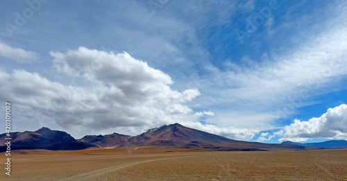 Bolivian Andes mountains in desert. Volcanic landscape. Vast extreme terrain. Impressive cloudy sky. Adventure. Road to volcano Ollague. Clouds over mountains.