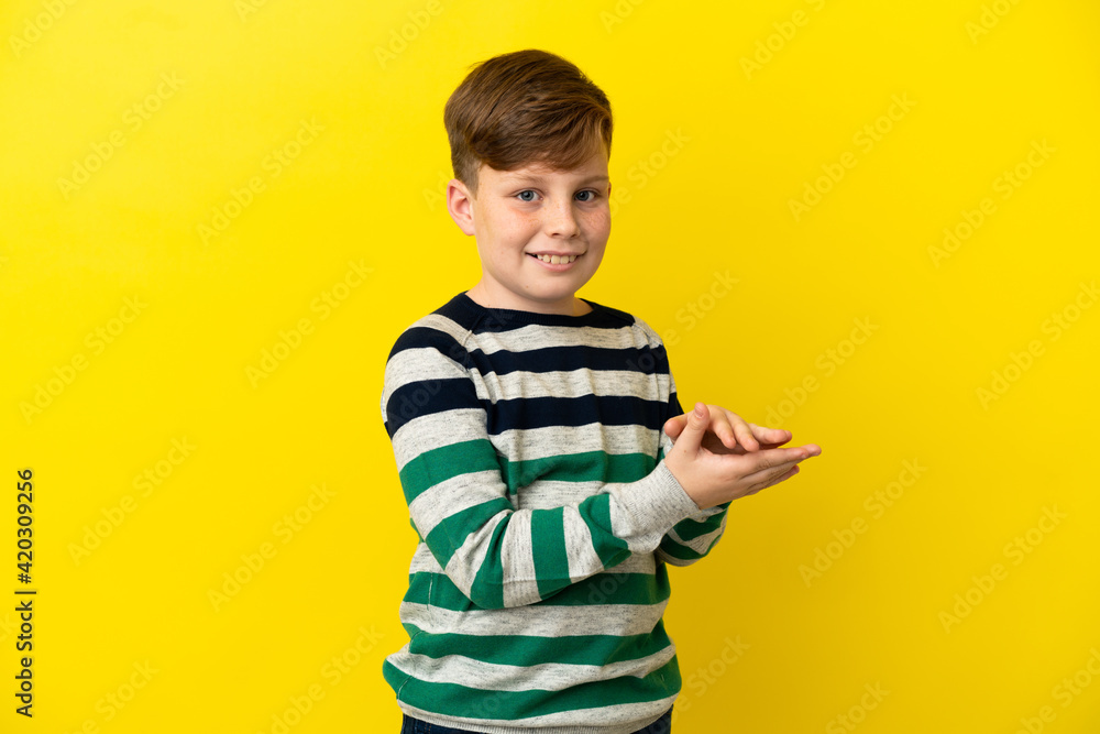 Little redhead boy isolated on yellow background applauding Little redhead boy isolated on yellow background applauding
