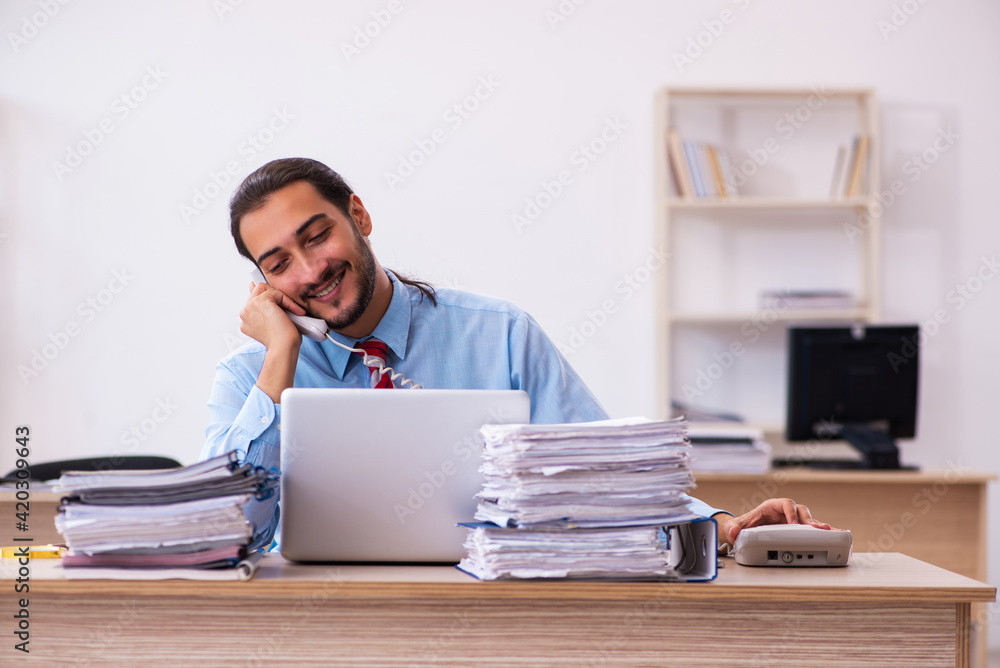 Young male employee unhappy with excessive work in the office Young male employee unhappy with excessive work in the office