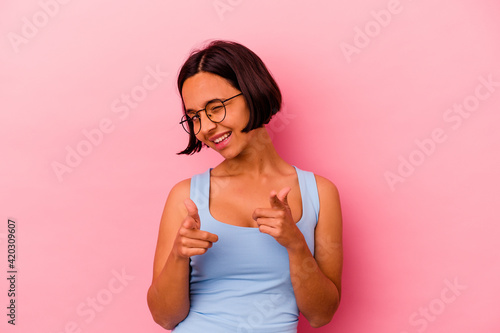 Young mixed race woman isolated on pink background pointing to front with fingers.