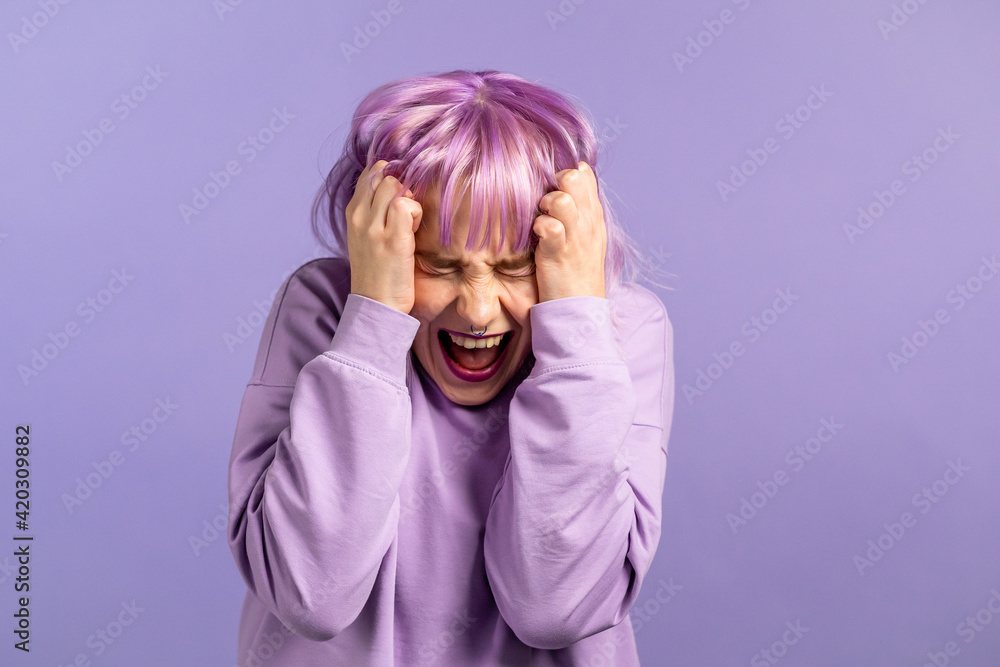 Frightened and screaming woman with dyed purple hair shocked isolated over violet background. Stressed and depressed pretty girl because of bad news.