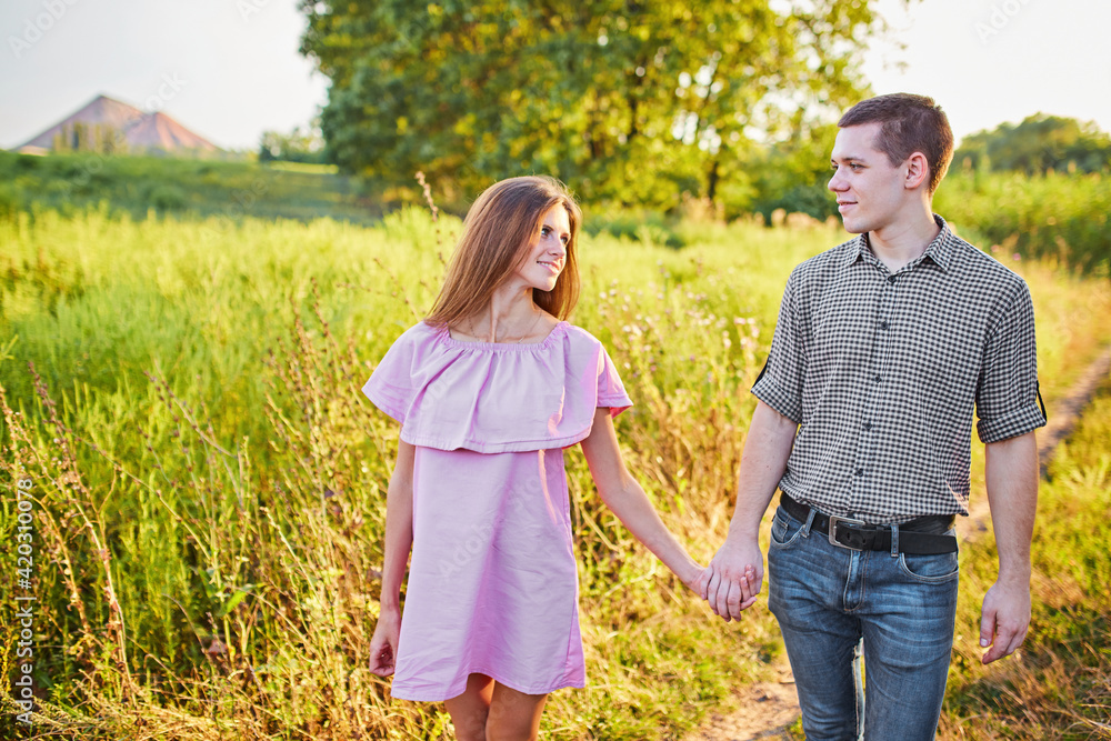 Fototapeta premium Shot of a young couple holding hands and running through the park.