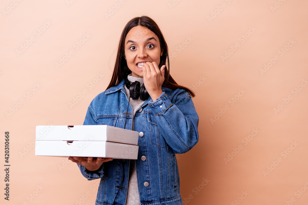 Young mixed race woman holding a pizza isolated biting fingernails, nervous and very anxious. Young mixed race woman holding a pizza isolated biting fingernails, nervous and very anxious.