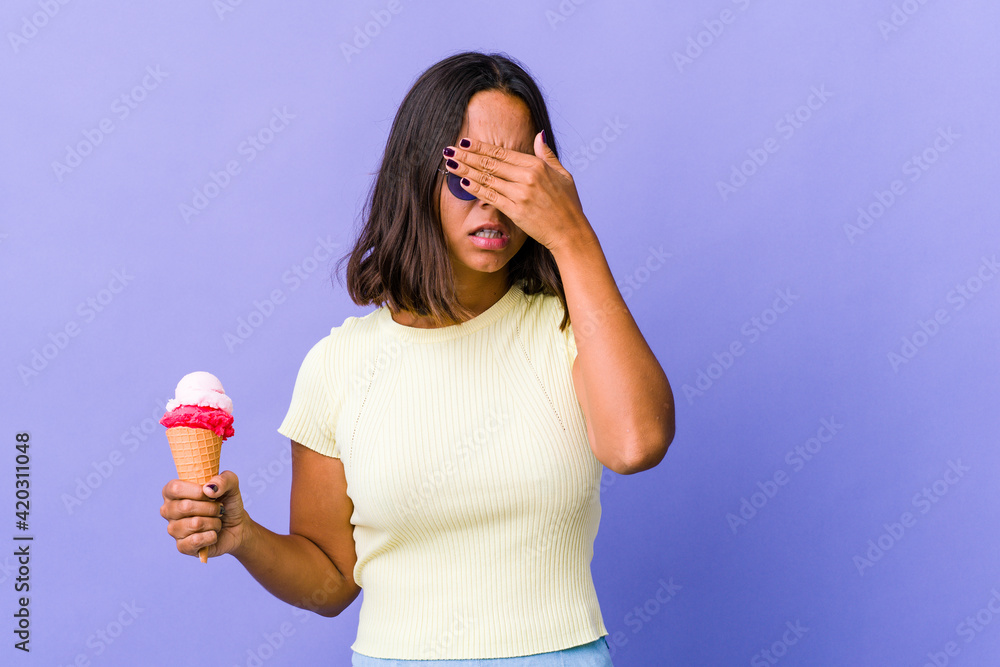 Young mixed race woman eating an ice cream afraid covering eyes with hands. Young mixed race woman eating an ice cream afraid covering eyes with hands.