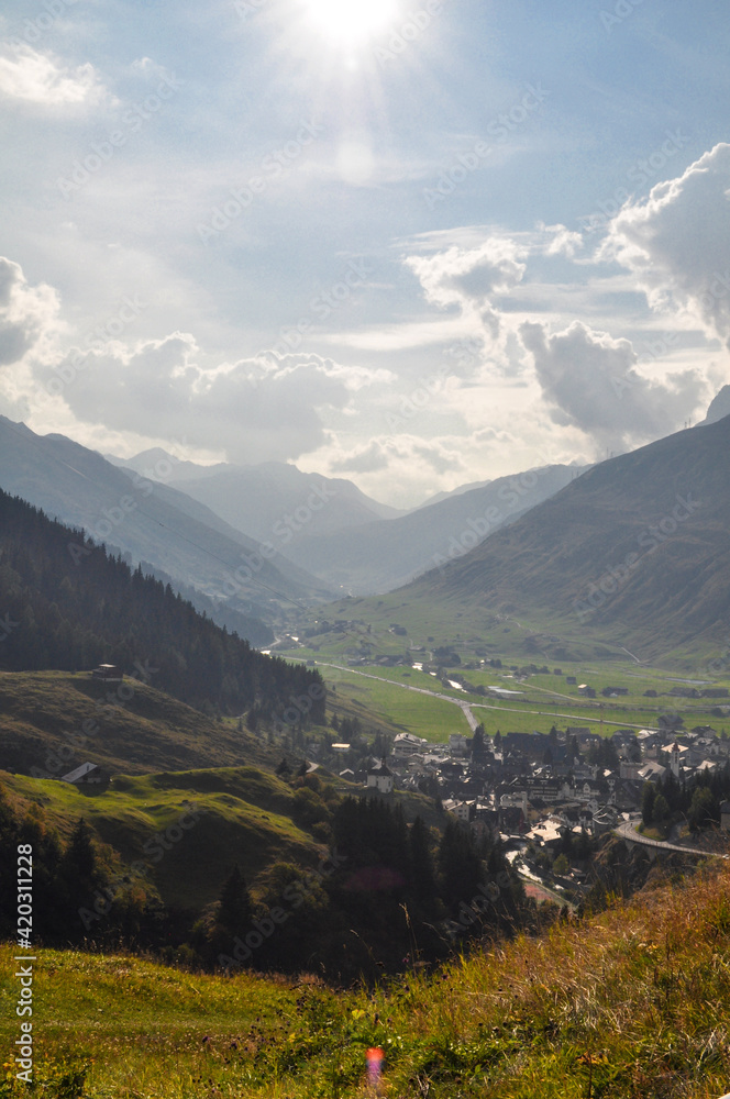 Naklejka premium View into a deep mountain valley with houses and roads directly against the sun - France