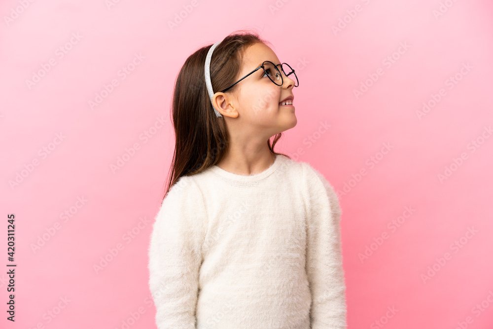 Little caucasian girl isolated on pink background looking up while smiling Little caucasian girl isolated on pink background looking up while smiling