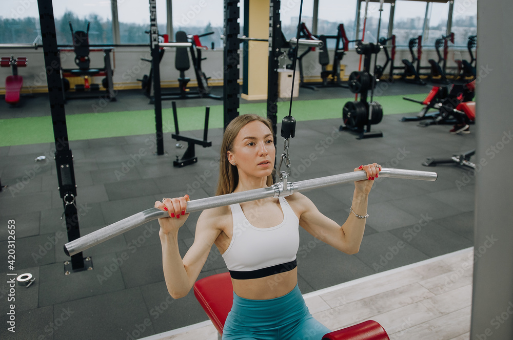 Beautiful young girl engaged in fitness in the gym. Brunette performs exercises on the simulator. Beautiful young girl engaged in fitness in the gym. Brunette performs exercises on the simulator.