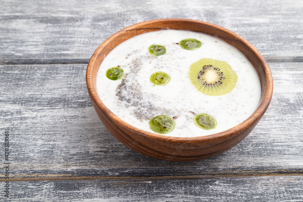 Yogurt with kiwi, gooseberry, chia and almonds in wooden bowl on gray wooden background. side view. Yogurt with kiwi, gooseberry, chia and almonds in wooden bowl on gray wooden background. side view.