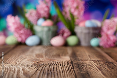 Easter background. Easter eggs and spring flowers. Rustic wooden table. Pastel colors bokeh. Place for typography.