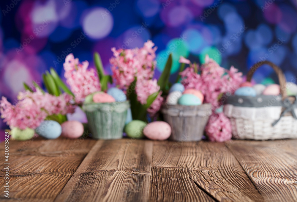 Easter background.  Easter eggs and spring flowers. Rustic wooden table. Pastel colors bokeh. Place for typography.
