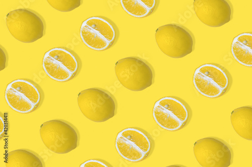 Trendy summer pattern with yellow lemon slice and whole lemon on illuminating yellow background.