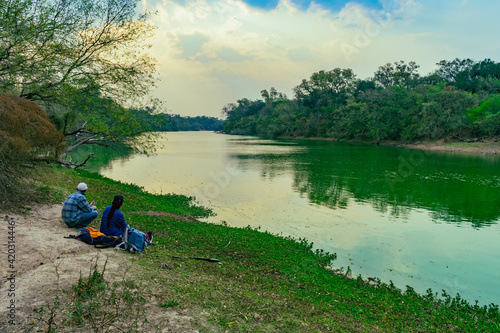 persona sentada al costado de lago mirando al horizonte