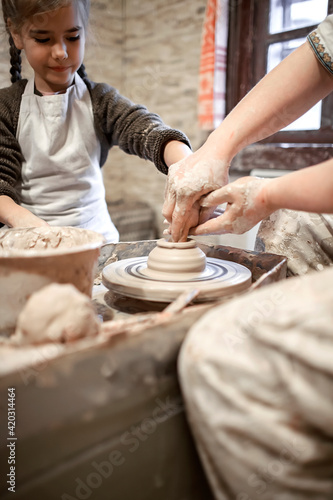 Girl playing with modeling clay on pottery wheel at workshop, craft art, artisan hobby and leisure