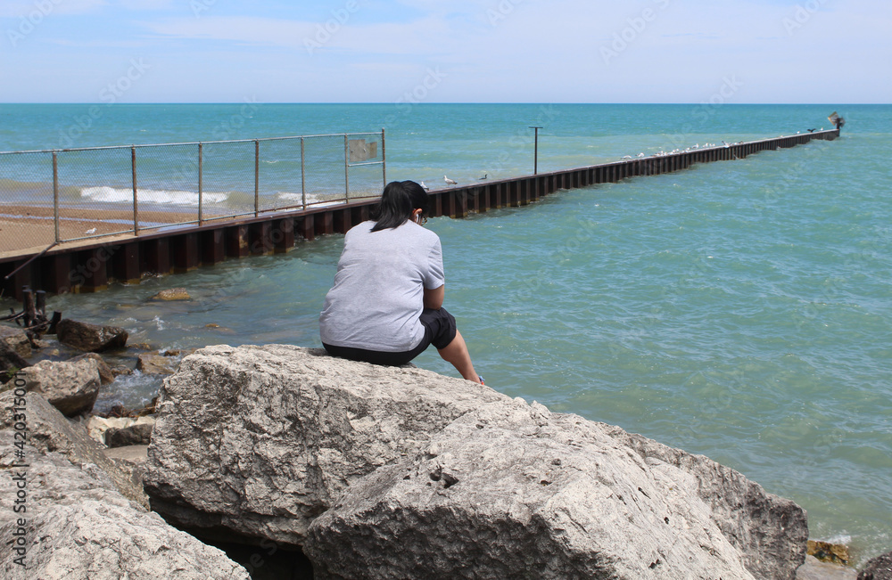 Woman sitting on the rocks at Lake Michigan at Evanston's South Boulevard Beach
