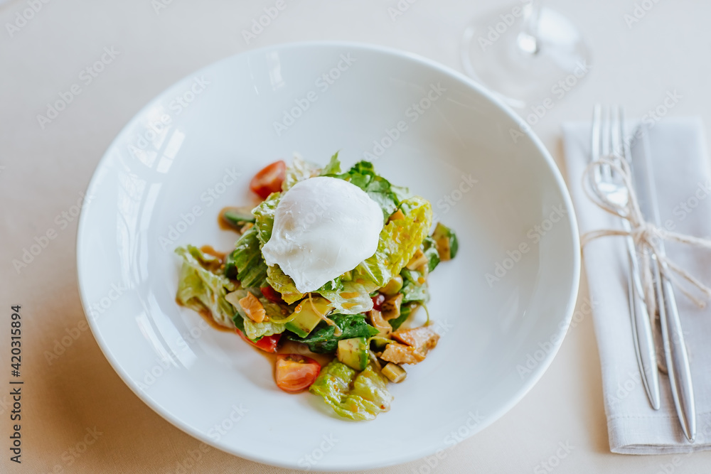 Avocado salad with chicken fillet and poached egg on white plate. Avocado salad with chicken fillet and poached egg on white plate.