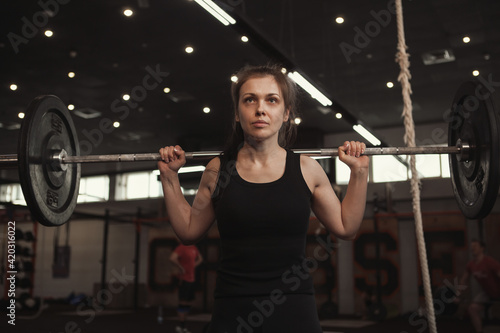 Low angle shot of a sportswoman working out with barbell at functional training gym