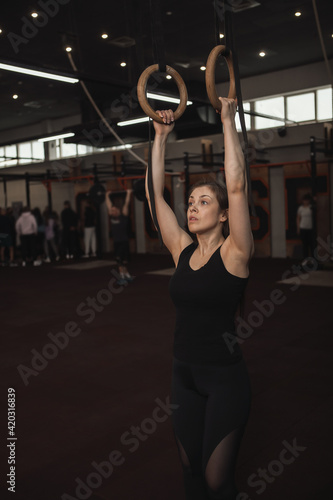 Vertical shot of a sportswoman exercising on gymnastic rings at the gym