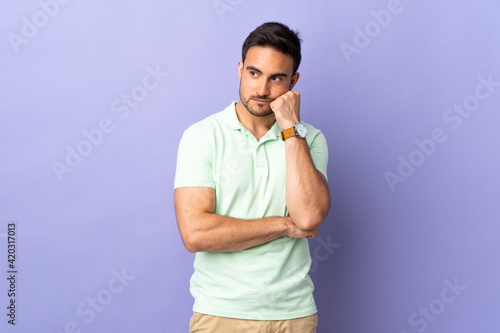 Young handsome man isolated on purple background with tired and bored expression