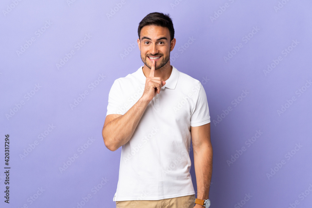 Young handsome man isolated on purple background showing a sign of silence gesture putting finger in mouth Young handsome man isolated on purple background showing a sign of silence gesture putting finger in mouth