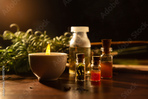 Aromaterapia e fitoterapia. Terapia holística. Vidros com óleos essenciais, vela acesa e ervas ao fundo. photo