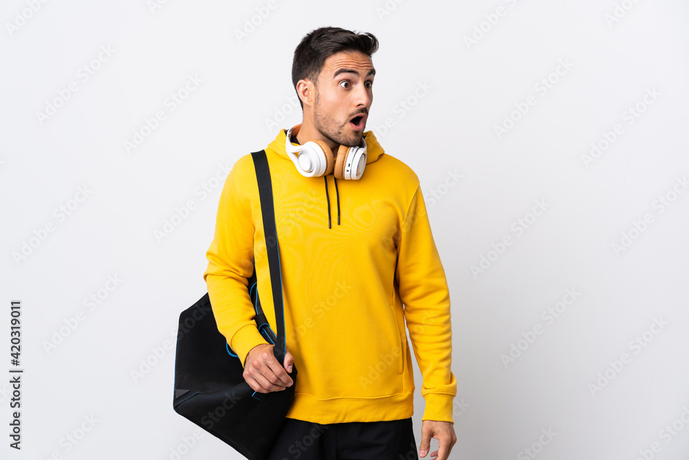 Young sport man with sport bag isolated on white background doing surprise gesture while looking to the side Young sport man with sport bag isolated on white background doing surprise gesture while looking to the side