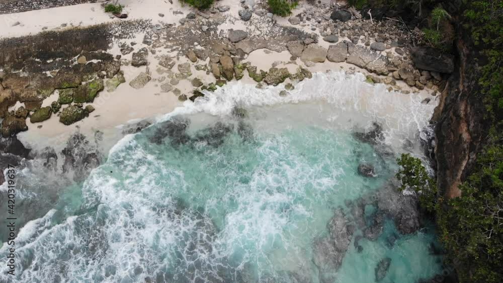 Aerial top view of waves break on rocks in a blue ocean. Sea waves on ...