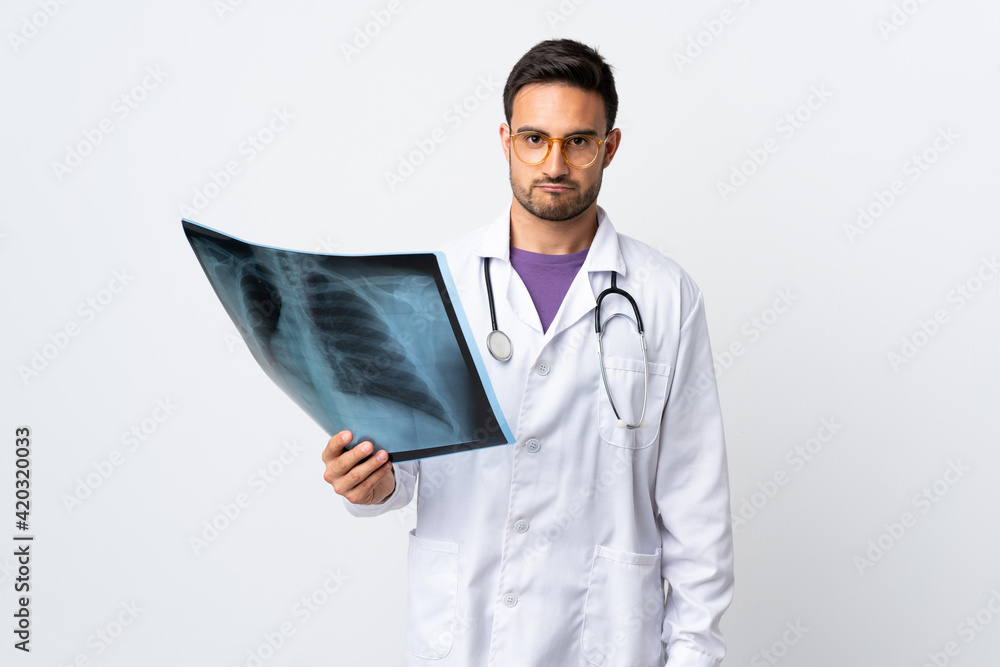 Young doctor man holding a radiography isolated on white background sad Young doctor man holding a radiography isolated on white background sad